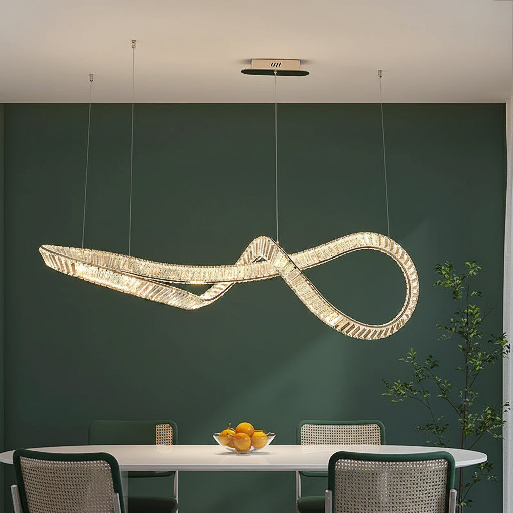 Modern chandelier shaped like scissors hanging above a dining table with fruit bowl and chairs.
