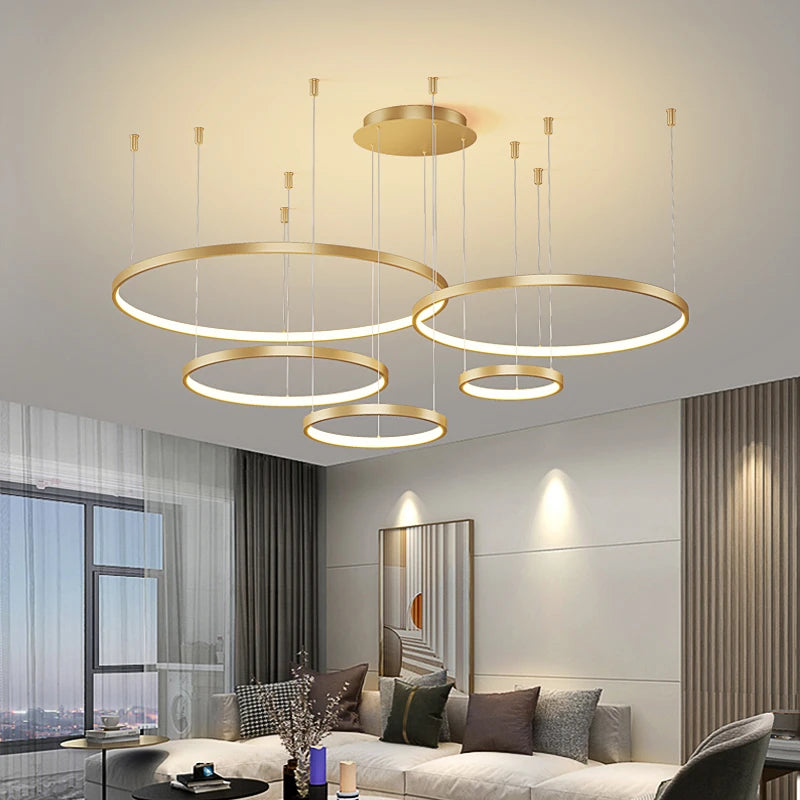 CIRCLETS five gold-finish LED rings, lit, at staggered heights in a living room
