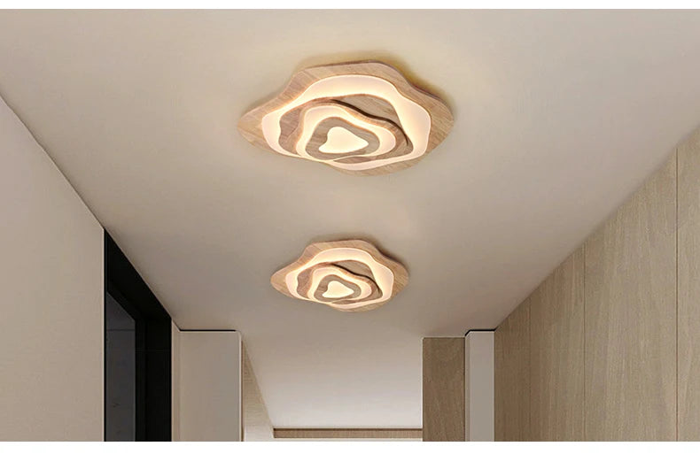 MAPLE layered wavy ceiling lights in beige and wood tones, lit, along a hallway