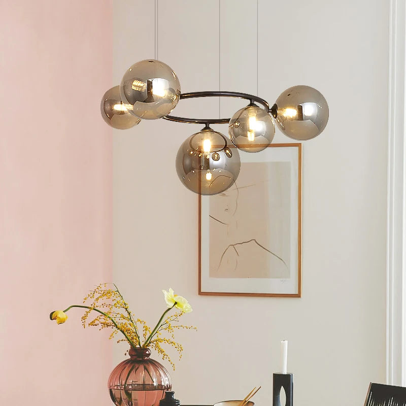 GLOBIQUE smoky amber glass globes on a dark ring frame over a pink-walled room