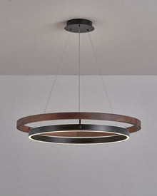 Wide walnut ORLUNEA chandelier installed low, emphasizing the glowing circular diffuser.