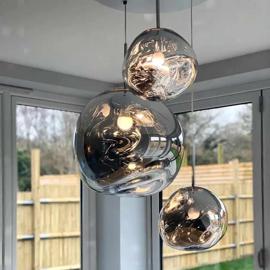 LAVA three silver mirrored pendants, lit, in front of patio doors