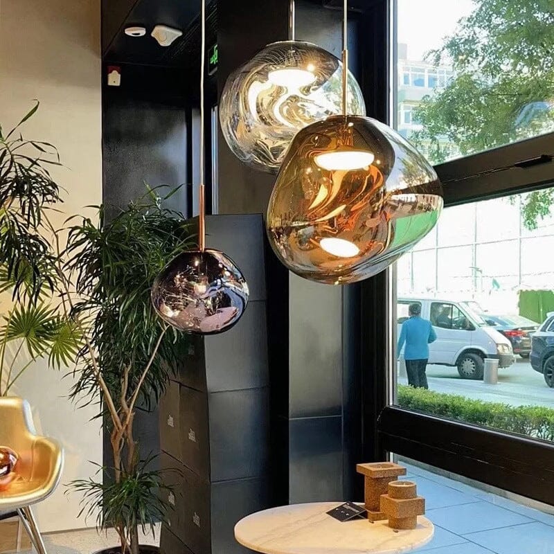 LAVA silver, gold and rose gold pendants, lit, beside a large street-facing window