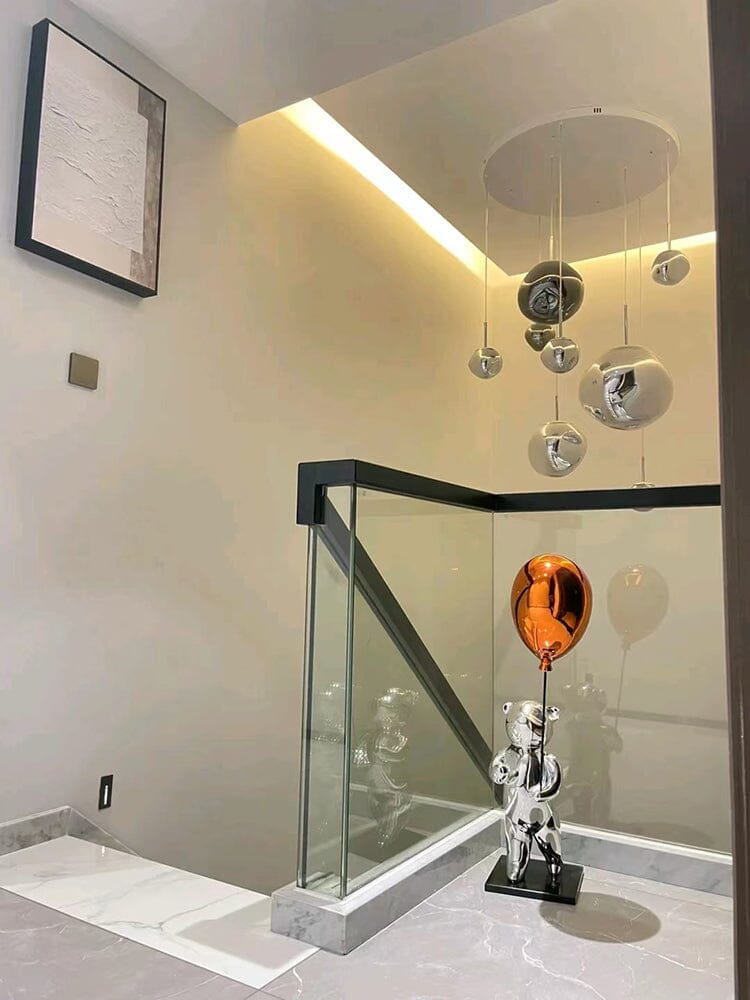 LAVA silver and rose gold pendants hanging in a stairwell beside a glass balustrade
