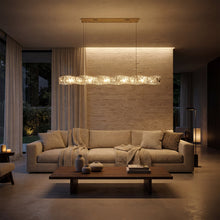 SEVRAYA glowing crystal chandelier above a taupe sofa and wooden coffee table at dusk
