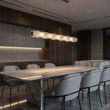 SEVRAYA gold crystal pendant above a long stone dining table in a dark contemporary room
