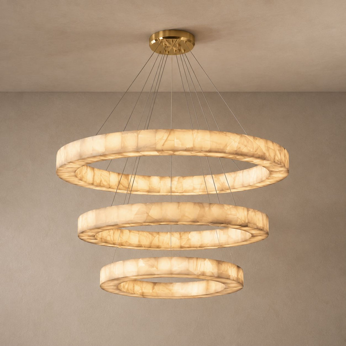 AINA three-tier alabaster ring chandelier on a mushroom taupe background with natural canopy shadows