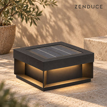 ALYRA Black solar outdoor light with a recessed solar panel and warm side lighting in a limestone courtyard