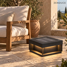 ALYRA Black solar ground light beside a teak lounge chair on a sunlit limestone patio