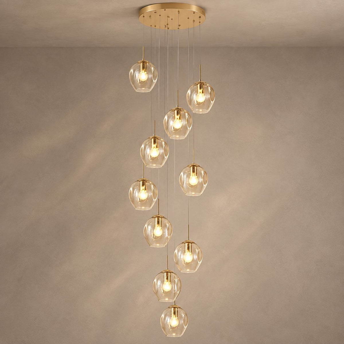 ELIOS cascading chandelier with ten champagne glass globes and gold fittings on mushroom taupe plaster