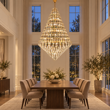 SERAPHINE gold crystal chandelier over a dining table in a high-ceiling room