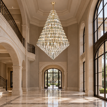SERAPHINE gold crystal chandelier in a triple-height limestone foyer