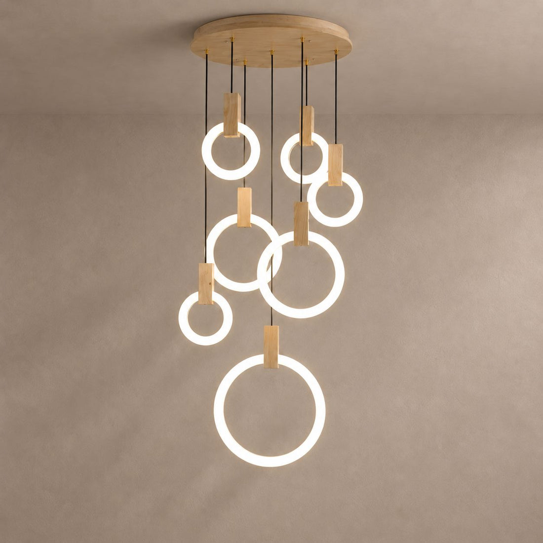 HALO seven-ring willow wood chandelier with luminous white rings on a mushroom taupe plaster background