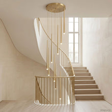 CINDRA gold cascading acrylic chandelier in a bright open stairwell