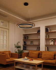 Walnut ORLUNEA ring chandelier warming a lounge with rust-colored sofas and open shelving.