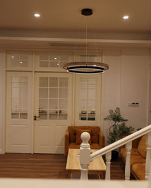 ORLUNEA chandelier viewed across a staircase above a rust-colored living-room seating area.
