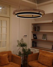 Close room view of the walnut ORLUNEA rings above two rust-colored armchairs.