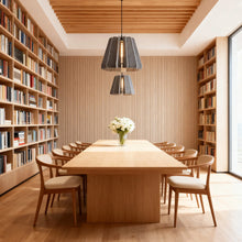 FELLA - Gray felt pendants over a long dining table between bookshelves