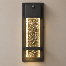 NUVIEL Dusk to Dawn Sensor wall light on mushroom taupe with natural shadow: small photocell, black aluminum backplate and clear illuminated bubble glass.