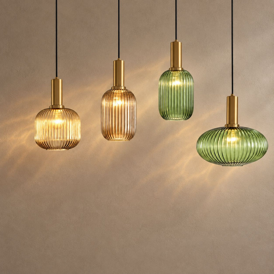 OMNAY four ribbed glass pendants in amber and green with gold-finish caps, lit