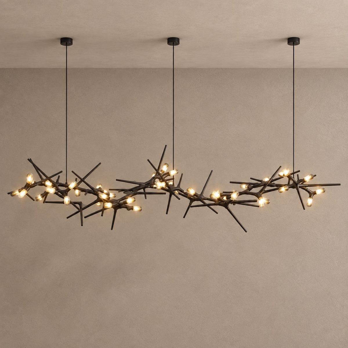 ONYX black branching chandelier with warm capsule lights against mushroom taupe plaster and natural ceiling shadows