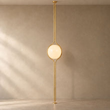 ORELIA Brass floor-to-ceiling globe lamp on a mushroom taupe background