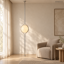 ORELIA silver globe lamp beside a taupe armchair in a sunlit reading corner