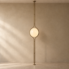 ORELIA Vintage Brass floor-to-ceiling globe lamp with natural floor and wall shadows