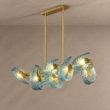 PAVO dining chandelier with teal textured glass leaves and brass linear frame on mushroom taupe plaster