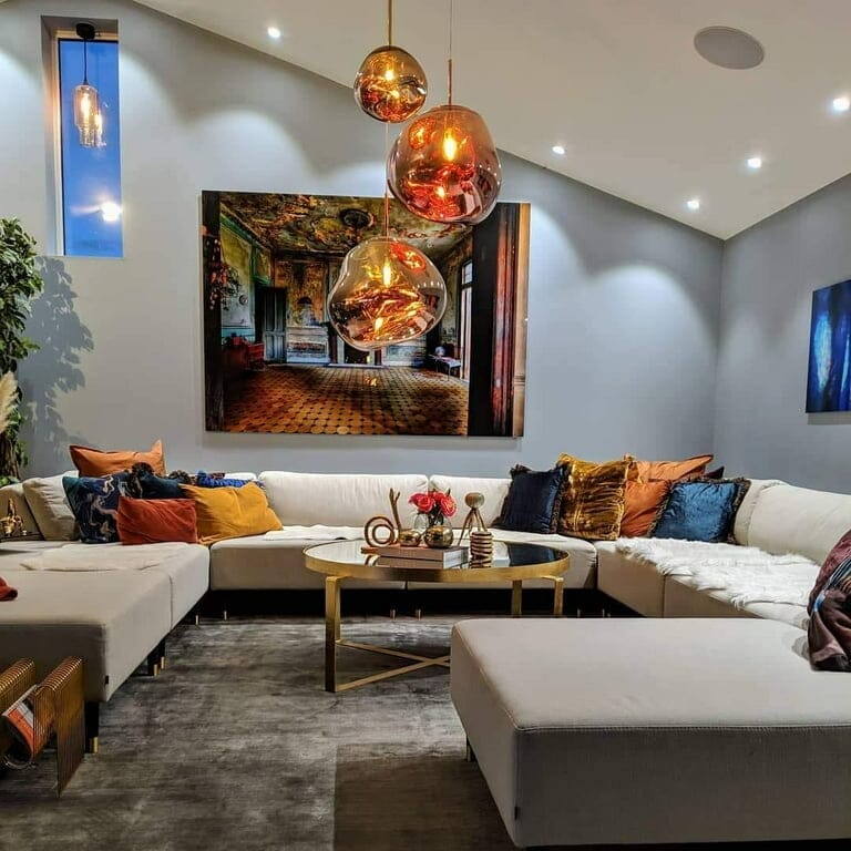 LAVA two rose gold pendants in front of a large painting above a white sectional