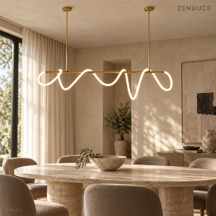 SELIA gold linear LED chandelier above a travertine dining table, with two round ceiling mounts and a flowing illuminated tube
