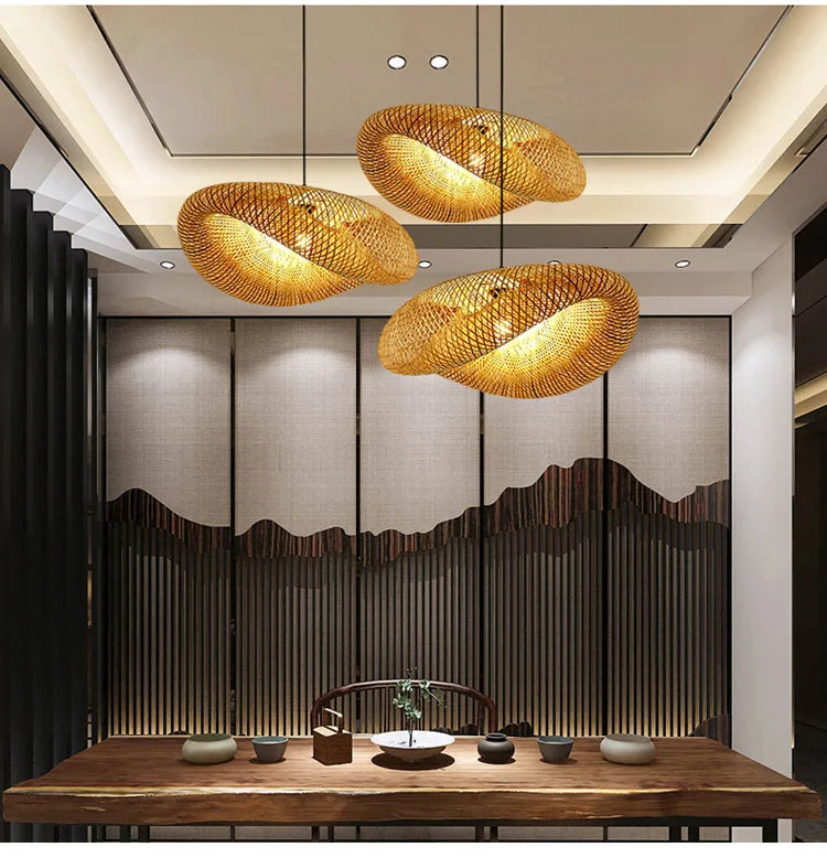 BASK three oval woven bamboo pendants, lit, over a long wooden table