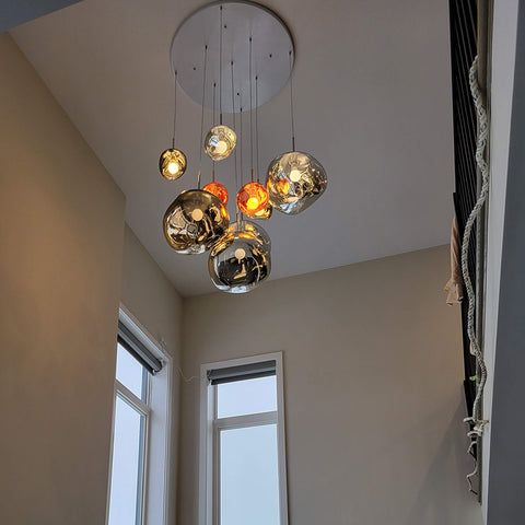 LAVA DROPS cluster of mixed-color molten pendants on a round canopy in a tall stairwell
