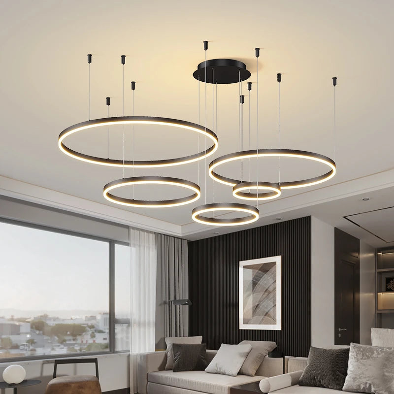 CIRCLETS five black LED rings, lit, hanging at staggered heights in a living room