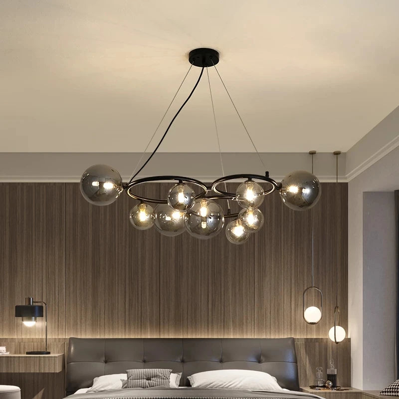 GLOBIQUE smokey gray glass globes on a dark ring frame, lit, above a bed