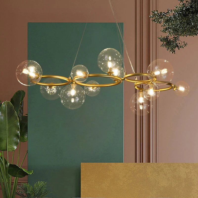 GLOBIQUE clear glass globes on a gold-finish ring frame, lit, by a green wall
