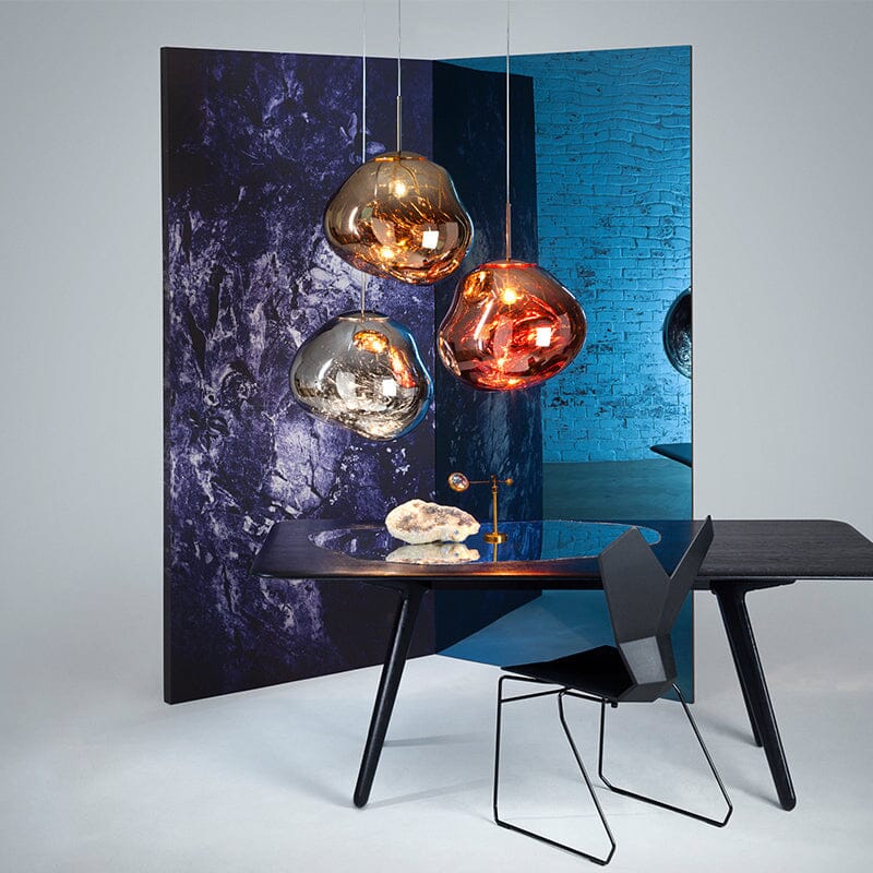 LAVA gold, rose gold and silver pendants above a black desk by a blue screen