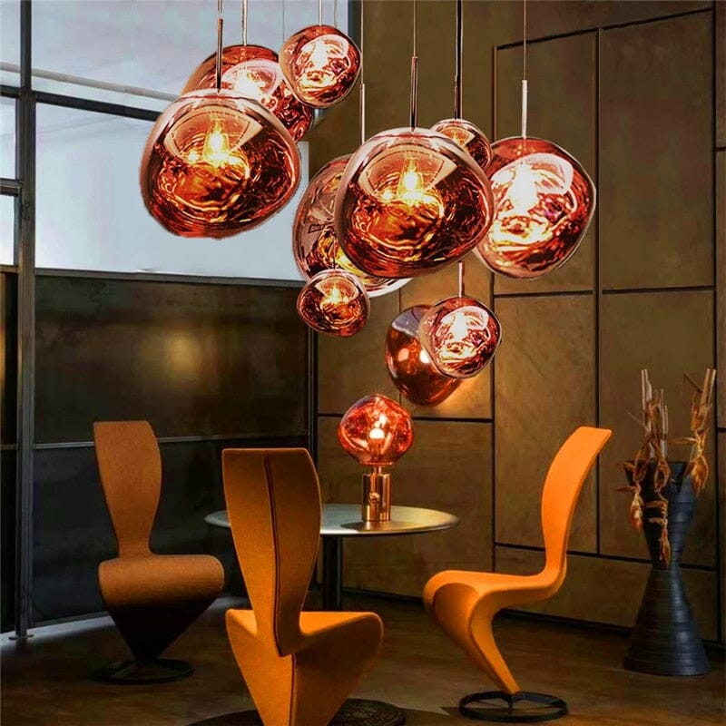 LAVA cluster of rose gold pendants above orange sculptural chairs